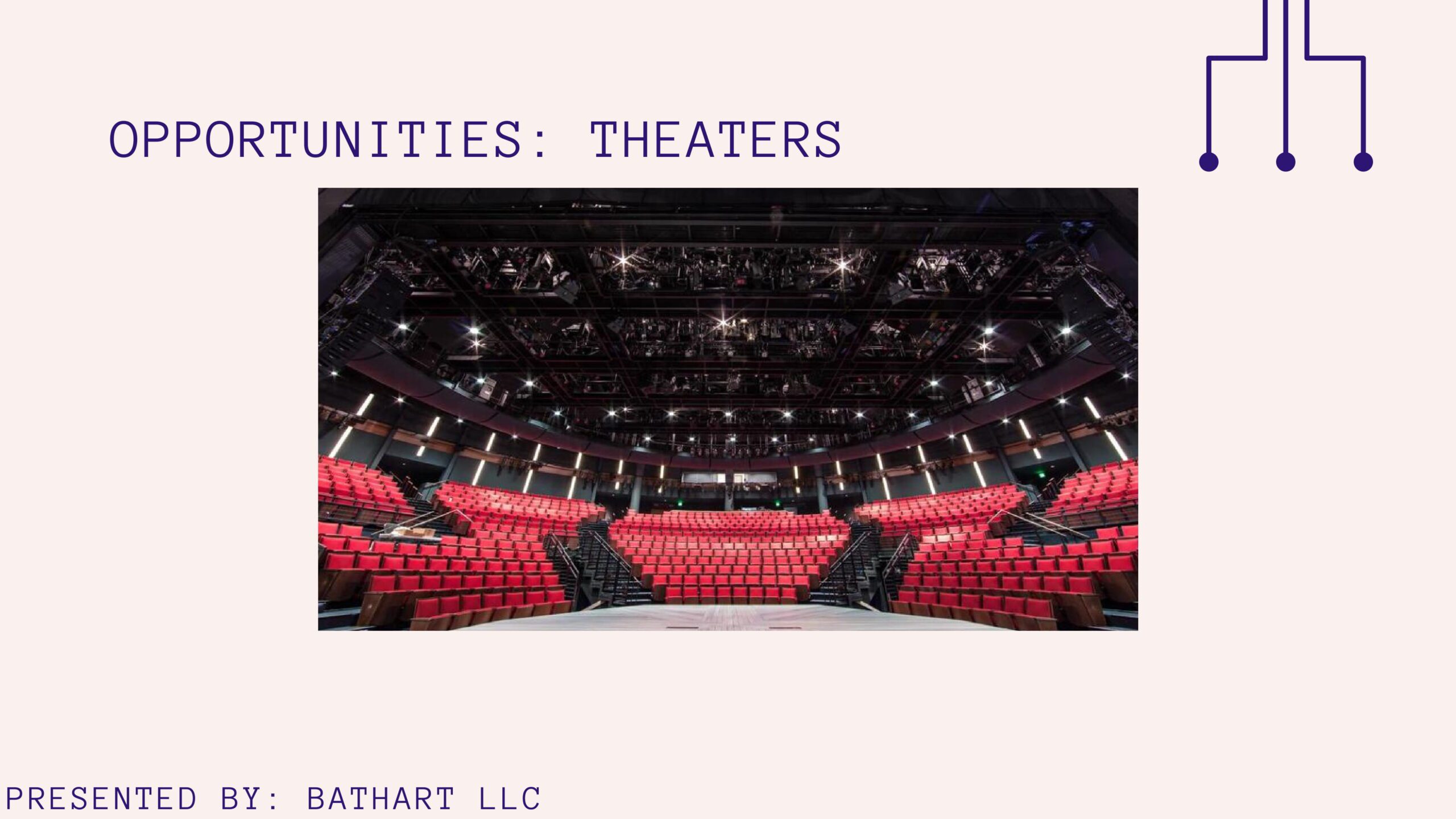 A large auditorium with red seats and black chairs.